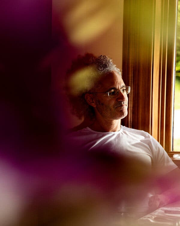 A portrait of Mr. Karp seated in a dim room close to a window with daylight streaming through. Half his face is illuminated.