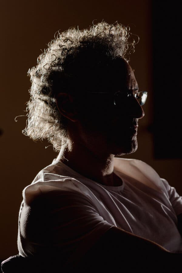 A moody portrait of Mr. Karp, who is shown mostly in shadow.