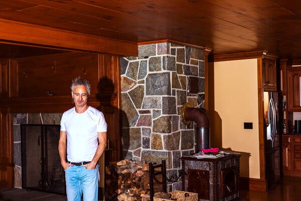 Wearing a white T-shirt and faded bluejeans, and with his hands in his pockets, Mr. Karp stands beside a wood-burning stove.
